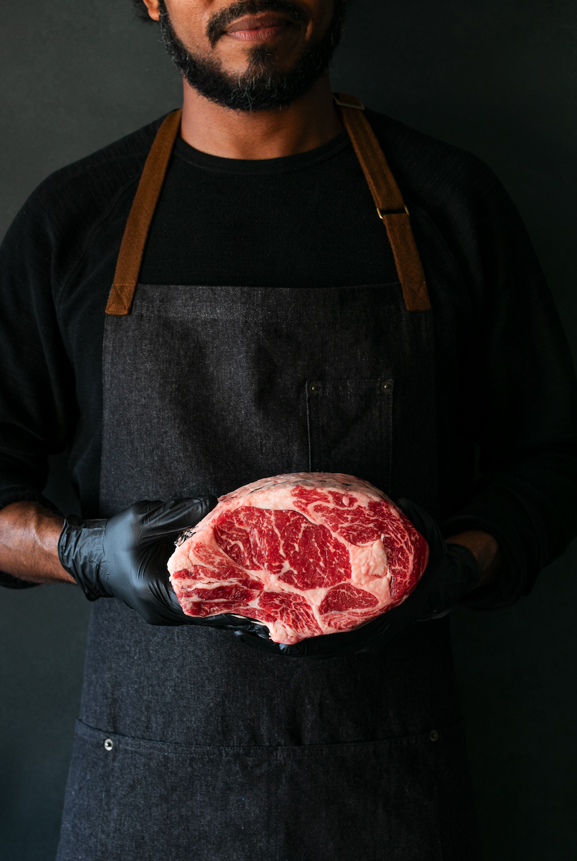 butcher holding a raw steak
