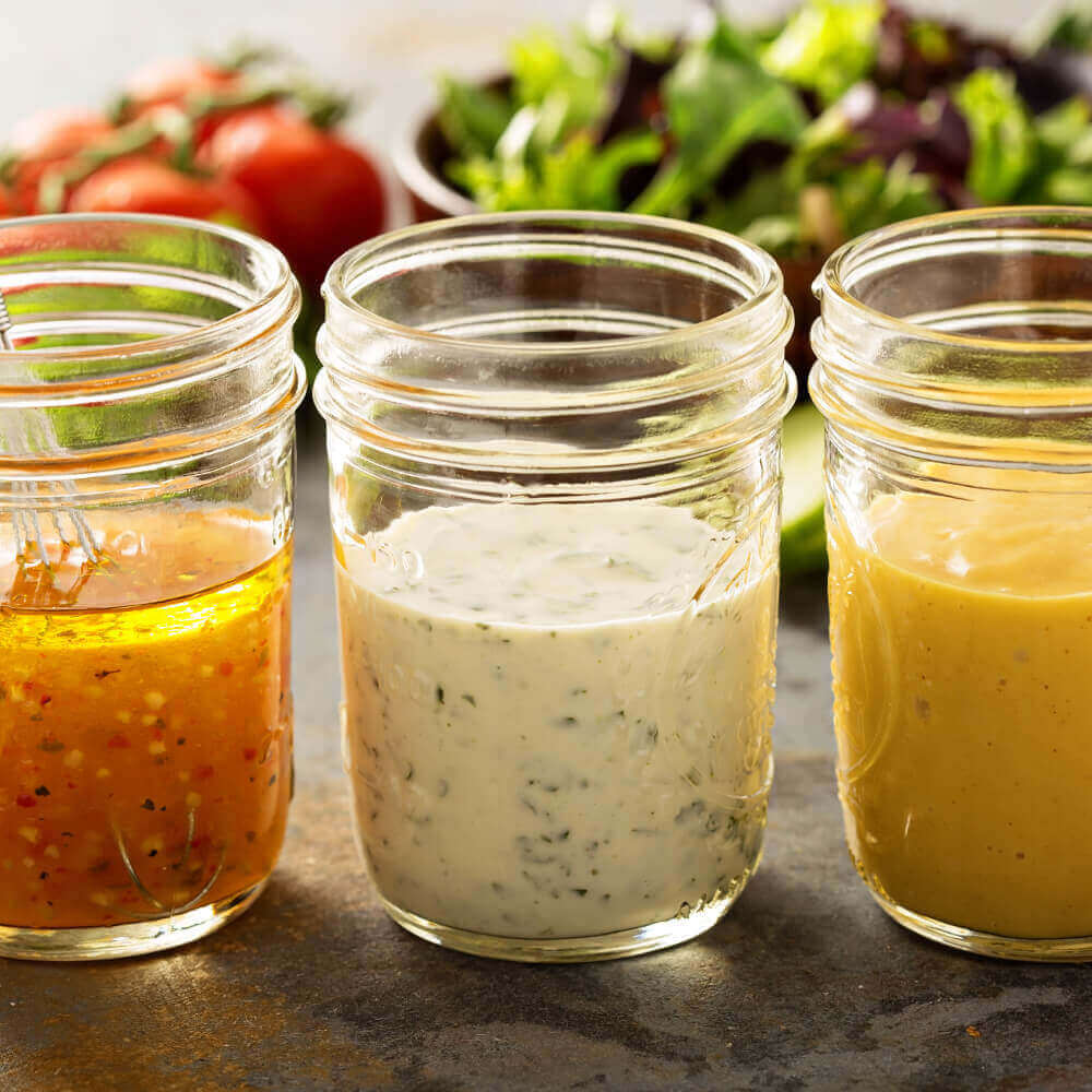 three mason jars with dressing