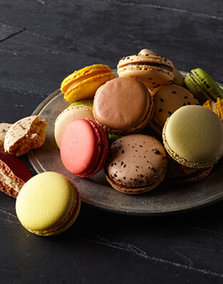 A plate stacked with brown, green, and yellow macarons