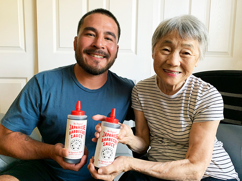 Justin and his mom holding bottles of barbecue sauce