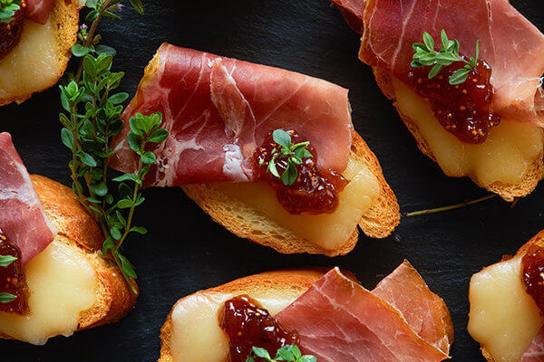 Crostini topped with fontina cheese, imported prosciutto, and fig jam