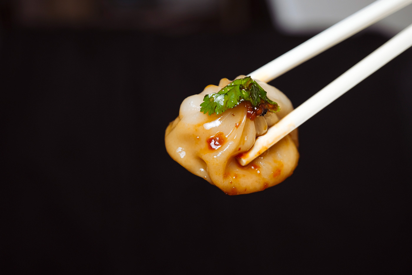 a dumpling dipped in sauce with chopsticks