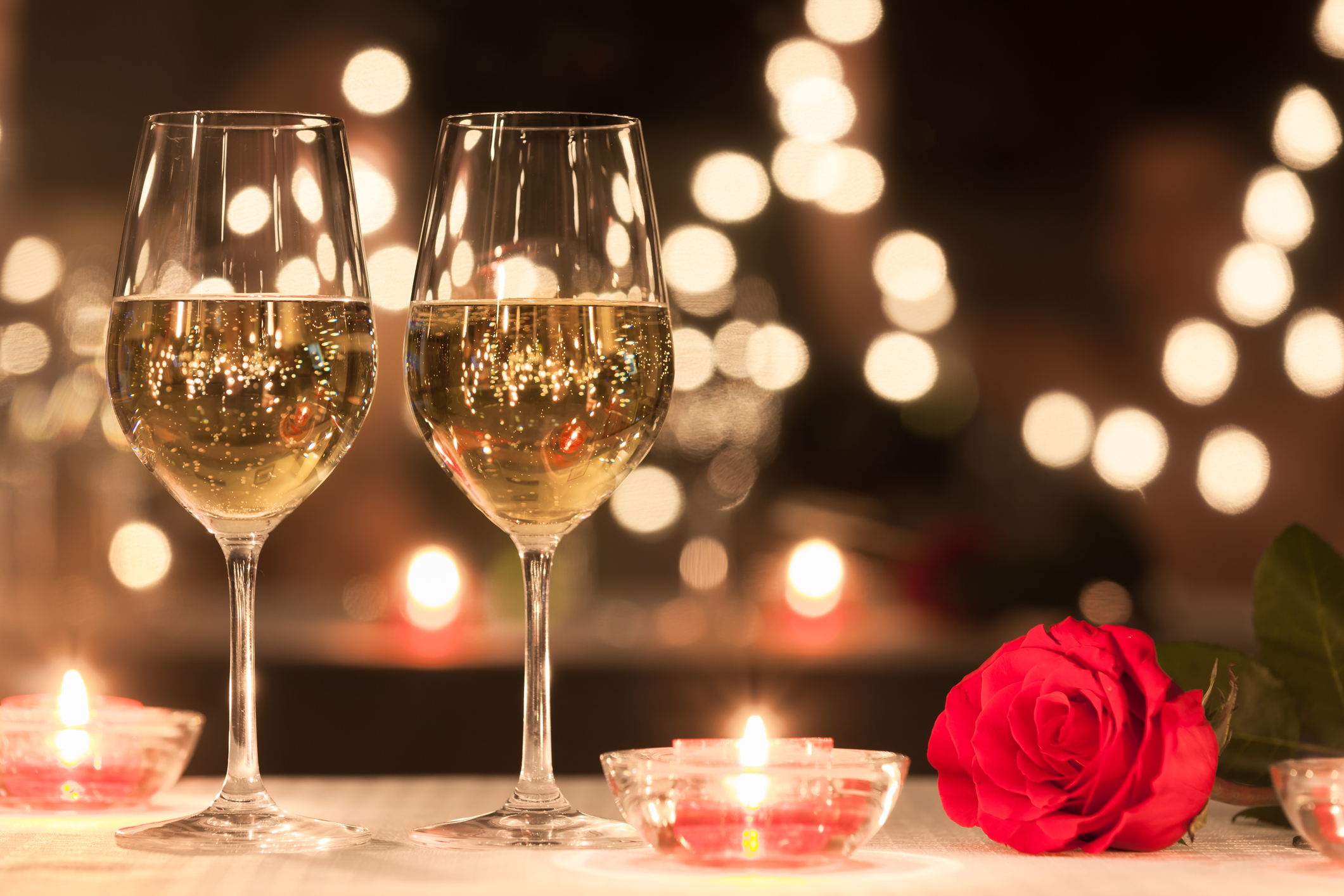 Champagne glasses candles and a rose