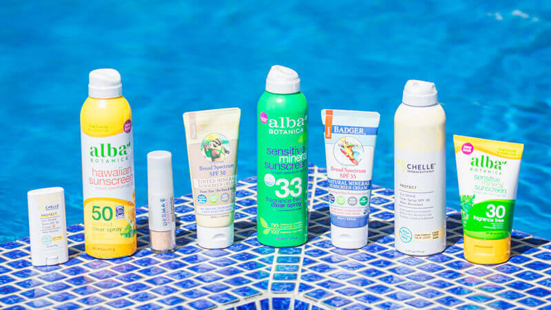 array of sunscreen products in front of a pool