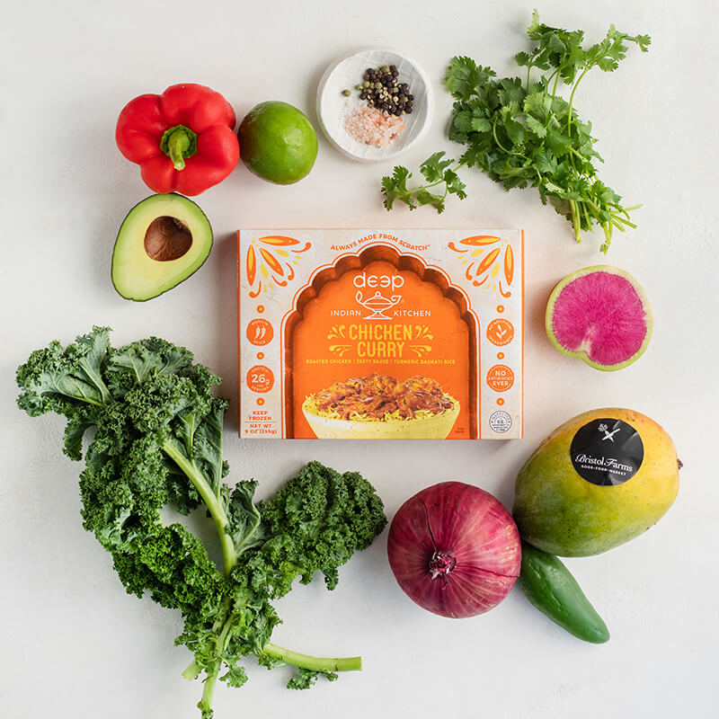 Box of chicken curry surrounded by vegetables 