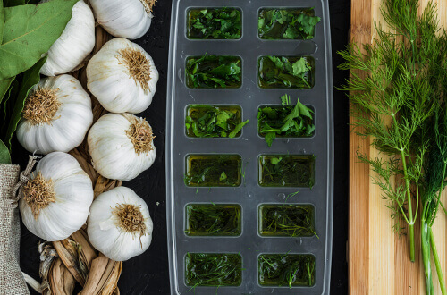 garlic heads and herbs in an ice cube tray